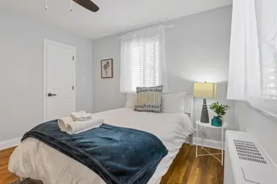 a white bedroom with a bed with a blue blanket on it at Cozy 2 BR in Short North Convenient Parking in Columbus