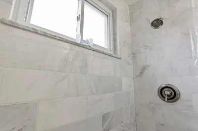 a white bathroom with a shower with a window at Cozy 2 BR in Short North Convenient Parking in Columbus