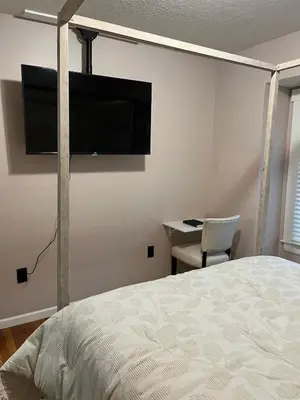 a bedroom with a bed and a flat screen tv on the wall at Sunny Lavender Canopy Retreat in Cleveland