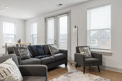 a living room with a couch and a chair and windows at 3 Stylish apartments near shops and entertainment in Cincinnati