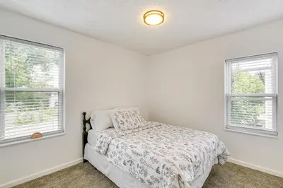 a white bedroom with a bed and two windows at Walkable Barberton Apartment 9 Mi to Akron! in Barberton