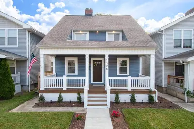 a blue house with a porch and an american flag at 5th Street Retreat Private Home OSU, Short North in Columbus