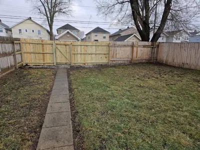 a backyard with a wooden fence and a yard withgrass at 5th Street Retreat Private Home OSU, Short North in Columbus