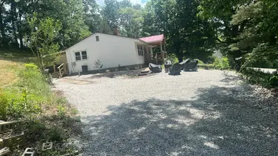 a house with a gravel driveway next to a building at Hillside country cabin in Lancaster