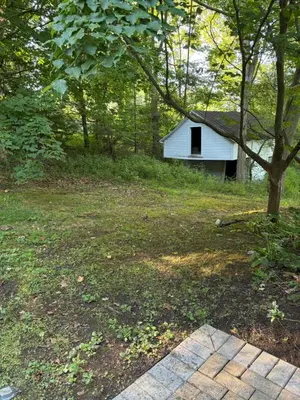 a small white house in the middle of a yard at Farmhouse Cabin in Ashland