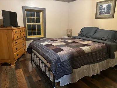 a bedroom with a bed and a dresser and a television at Farmhouse Cabin in Ashland