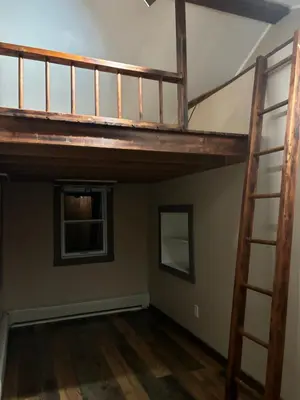 an attic room with a loft bed and a ladder at Farmhouse Cabin in Ashland