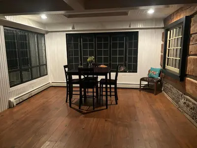 a dining room with a table and chairs and windows at Farmhouse Cabin in Ashland
