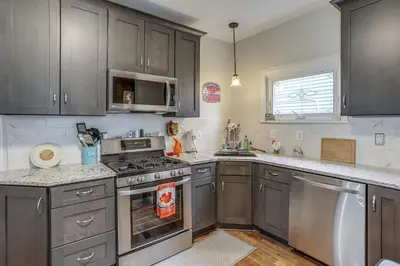 a kitchen with gray cabinets and stainless steel appliances at 3 Mi to Cedar Point Sunny Sandusky Home with Yard in Sandusky