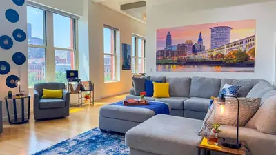 a living room with couches and a painting of a city at Downtown Cleveland- Steps to Sports & Events condo in Cleveland