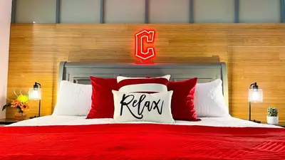 a bedroom with a red bed with a baseball sign on it at Downtown Cleveland- Steps to Sports & Events condo in Cleveland