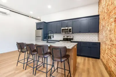 a kitchen with black cabinets and a counter with bar stools at Clay St Suite in Millersburg