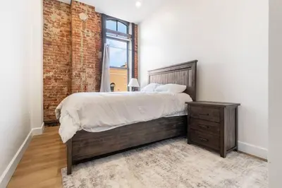 a bedroom with a large bed and a brick wall at Clay St Suite in Millersburg