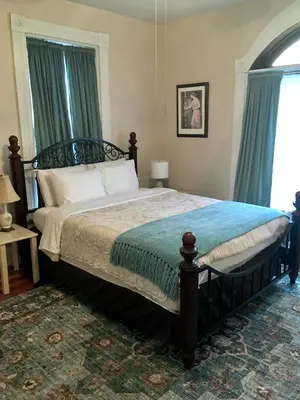 a bedroom with a large bed with blue curtains at Historic Upstairs Apartment in Bellevue