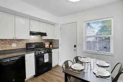 a kitchen with white cabinets and a table with chairs at The Northtowne Getaway in Columbus