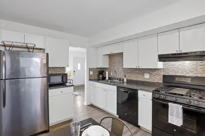 a kitchen with white cabinets and a stainless steel refrigerator at The Northtowne Getaway in Columbus