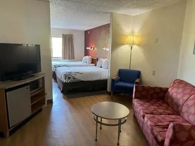 a hotel room with a couch and a bed and a tv at Sycamore Suites in Elyria