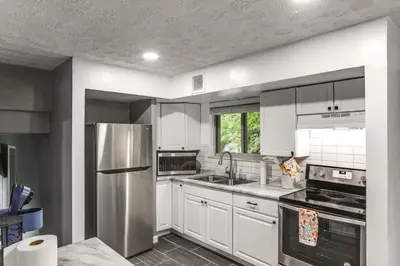 a kitchen with white cabinets and a stainless steel refrigerator at 4 Mi to MetroParks Ice Rink Pet-Friendly Getaway in Dayton