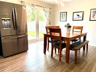 a kitchen with a table and a stainless steel refrigerator at Private Ranch- Entire Home - Hot Tub - Pets & Kids Welcome - King Bed - Fenced Backyard - Free WiFi in Gahanna