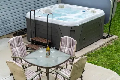 a table and chairs sitting next to a hot tub at Private Ranch- Entire Home - Hot Tub - Pets & Kids Welcome - King Bed - Fenced Backyard - Free WiFi in Gahanna