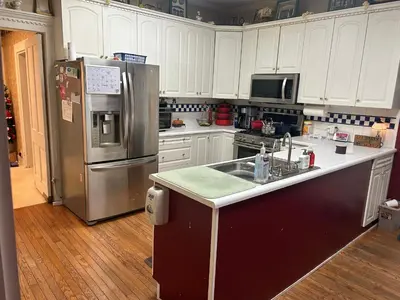 a kitchen with white cabinets and a stainless steel refrigerator at Main Oak Manor in Gallipolis