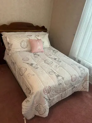 a bed with a white comforter and a pink pillow at Main Oak Manor in Gallipolis