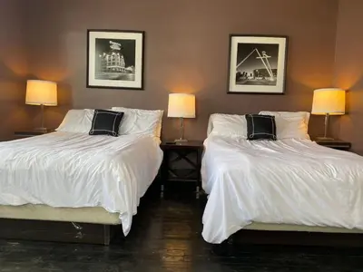 two beds with white sheets in a room with two lamps at Rare Find Sleeps 16 with 9 Beds 6BR plus WIFI in Cincinnati