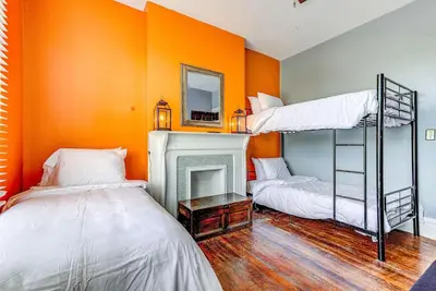 two beds in a room with an orange wall at Downtown Mansion with 7 Bedrooms 2.5 Baths Sleeps 20 in Cincinnati