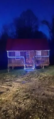 a house with a red roof is lit up at night at Cozy Cabin in New Lexington