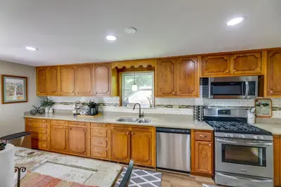 a kitchen with wooden cabinets and stainless steel appliances at Grandma Kellys Southeast Indiana Farmhouse! in Cedar Grove