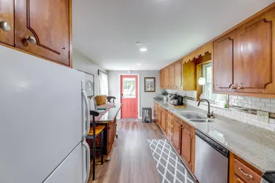 a kitchen with wooden cabinets and a red door at Grandma Kellys Southeast Indiana Farmhouse! in Cedar Grove
