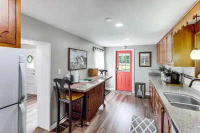 a kitchen with a counter and a red door at Grandma Kellys Southeast Indiana Farmhouse! in Cedar Grove