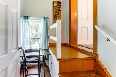 a stairway with a mirror and a chair at Grandma Kellys Southeast Indiana Farmhouse! in Cedar Grove