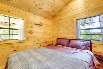 a bedroom with a bed in a log cabin at Stout Cabin with Fire Pit 1 Mi to Ohio River! in Stout