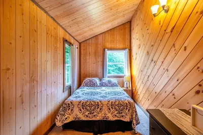 a bedroom with a bed in a wooden room at Whispering Pines Retreat in Zuck