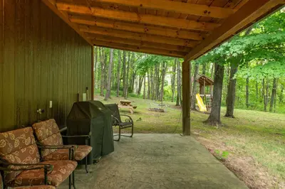 a porch with chairs and a table and a playground at Whispering Pines Retreat in Zuck