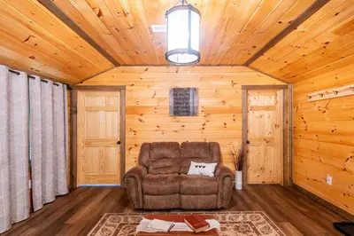 a living room with a chair in a log cabin at Whispering Pines Retreat in Zuck