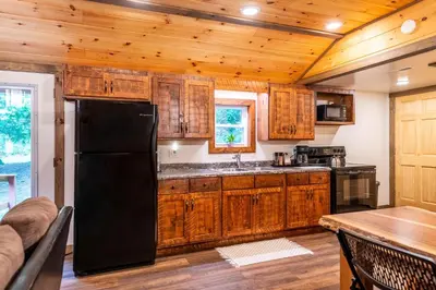 a kitchen with wooden cabinets and a black refrigerator at Whispering Pines Retreat in Zuck