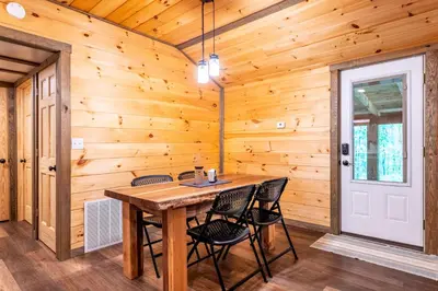 a wooden dining room with a table and chairs at Whispering Pines Retreat in Zuck