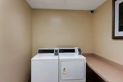 a small white refrigerator in a corner of a room at The Hilton Garden Inn in Grove City