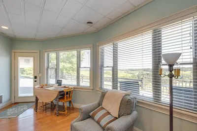 a living room with a chair and a table and windows at 4 Mi to German Village Studio with Hot Tub! in Millersburg