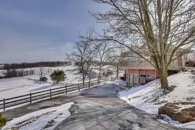 a road in a snowy field with a fence at Holmes With a View Studio Millersburg Retreat! in Millersburg