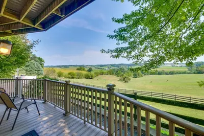 a deck with a chair and a view of a field at Amish Country Getaway with Pastoral Views! in Millersburg
