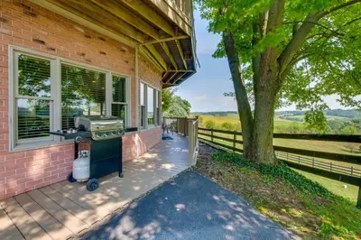 a barbecue on the side of a house with a tree at Amish Country Getaway with Pastoral Views! in Millersburg