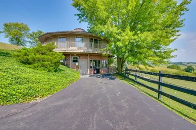 a house on a hill with a fence at Amish Country Getaway with Pastoral Views! in Millersburg