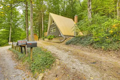 a house in the woods next to a dirt road at Carrollton Cabin with Patio and Fire Pit! in Carrollton