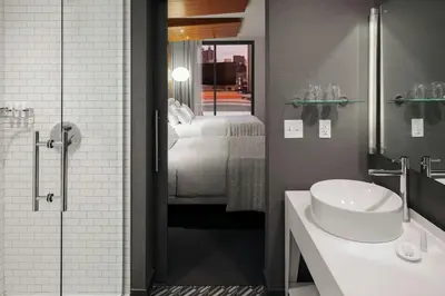 a bathroom with a sink and a bedroom with a bed at Le Meridien Columbus, The Joseph in Columbus