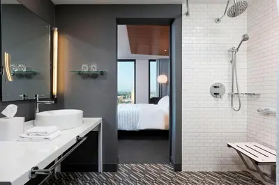 a bathroom with a sink and a shower and a bed at Le Meridien Columbus, The Joseph in Columbus