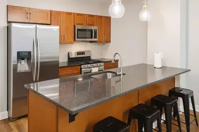 a kitchen with a stainless steel refrigerator and wooden cabinets at Modern Luxe Suite Rock Hall, Stadiums, Casino in Cleveland