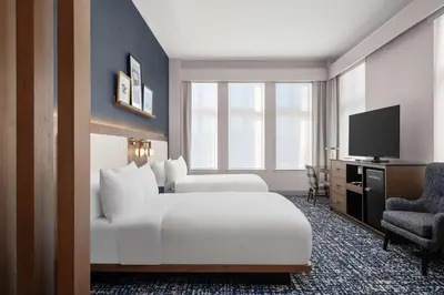 a hotel room with two beds and a television at The Well House Hamilton, Tapestry Collection By Hilton in Hamilton